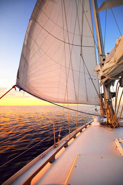 Valkoinen jahti purjehtii tyynessä vedessä auringonlaskun aikaan. Värikäs iltataivas, heijastuksia vedessä. Brittany, Ranska - Valokuva, kuva