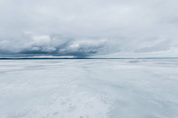 Téli táj. Kilátás a befagyott hóval borított tóra. Erdő a háttérben. Viharos felhők. Onega-tó, Karelia, Oroszország - Fotó, kép
