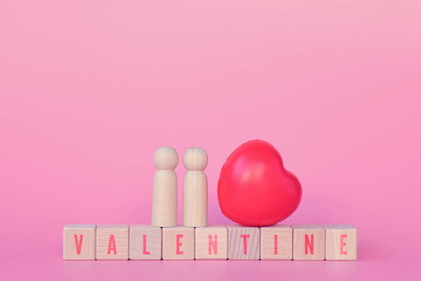 Valentýn a milostný koncept. Pár dřevěných panenek s červeným srdcem ukázat lásku během Valentýna festivalu. Červený text valentine na dřevěné kostky na růžovém pozadí kopírovat prostor. - Fotografie, Obrázek