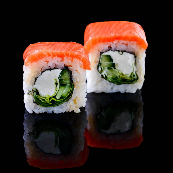 Concept of Asian cuisine. Two rolls of sushi with different fillings on a black background for Japanese menu cafe, restaurant, sushi bar. two sushi rolls couple isolated with reflection - Фото, изображение