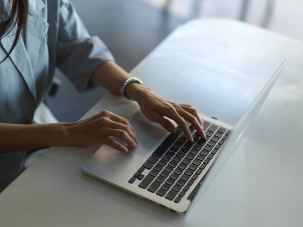 Oříznutý záběr ženských rukou na klávesnici notebooku na stole - Fotografie, Obrázek