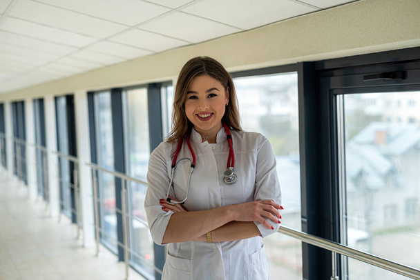 Retrato de hermosa enfermera sonriente en uniforme blanco con estetoscopio mirando a la cámara y sonriendo. Estudiante de medicina - Foto, imagen