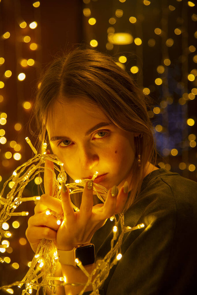 Portrait of a girl with a garland in her hands on a glowing background. - Foto, Imagem