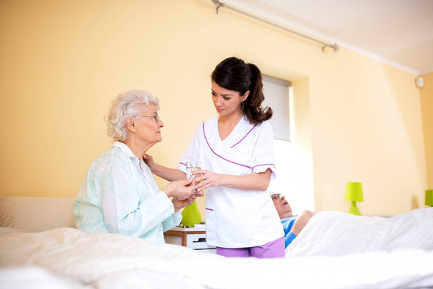 Two ladies working together, doctor and her nursing facility patient, nursing home concept - Photo, Image