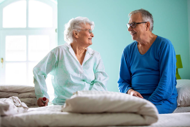 Senior man and elder woman sitting on the bed in a nursing home, and chatting - Φωτογραφία, εικόνα