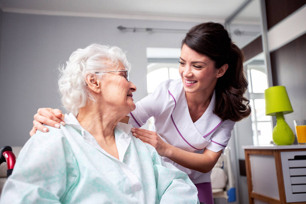 Ladies having a friendly conversation, diligent nurse and senior resident patient, doctor patient concept - Фото, зображення
