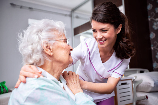 Ladies having a friendly conversation, diligent nurse and senior resident patient, doctor patient concept - Фото, изображение