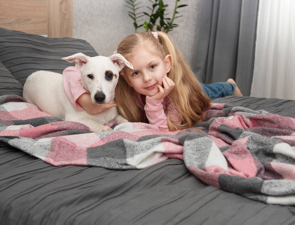Šťastné dítě se psem. Portrétní dívka s domácím mazlíčkem. Dívka a bílý Jack Russell - Fotografie, Obrázek