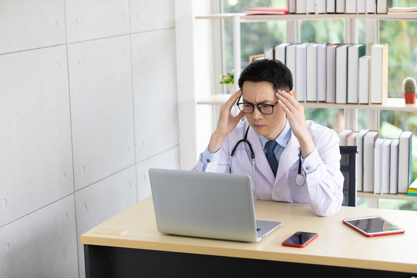 grave joven asiático médico hablando con su compañero de trabajo a través de chat de vídeo en línea con el ordenador en el hospital - Foto, imagen