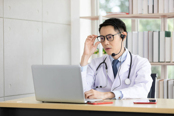 aasialainen lääkäri puhuu potilaan tai työtoverin kanssa online-videokeskustelun kautta tietokoneen kanssa sairaalassa - Valokuva, kuva