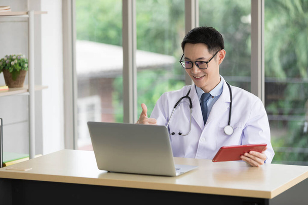 azjatycki lekarz rozmawia z pacjentem lub kolegą przez czat wideo online z komputerem w szpitalu - Zdjęcie, obraz
