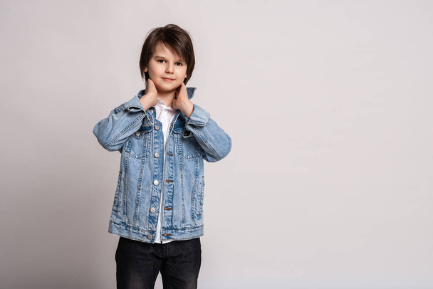 Handsome fashion little boy 11-13 years old in jean jacket posing in studio. Model Test. Fashion and people concept - Photo, Image