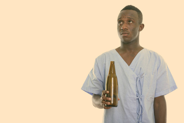 Estudio de un joven africano negro paciente pensando mientras sostiene la botella de cerveza - Foto, imagen
