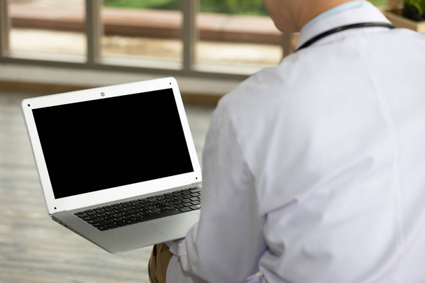 hinter männlichen Arzt tragen weißen Mantel suchen Monitor-Laptop-Computer mit leerem Bildschirm - Foto, Bild