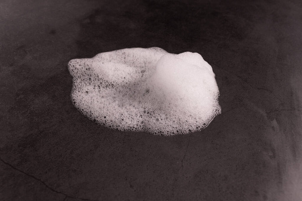 τήξη χιονιού σε μια μαύρη επιφάνεια και μια λακκούβα γύρω - Φωτογραφία, εικόνα