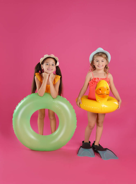 Cute little children in beachwear with bright inflatable rings on pink background - Foto, Bild