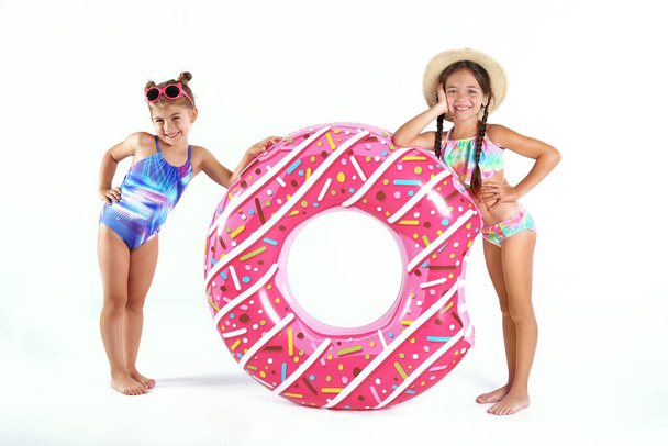 Cute little children in beachwear with bright inflatable ring on white background - Foto, Imagen