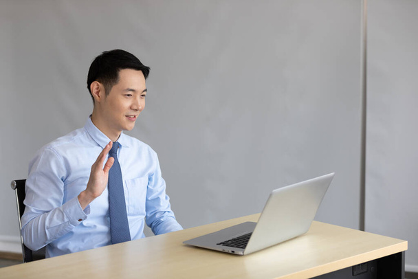 asian businessman talking and say hi to colleague through online video chat from laptop computer - Foto, imagen