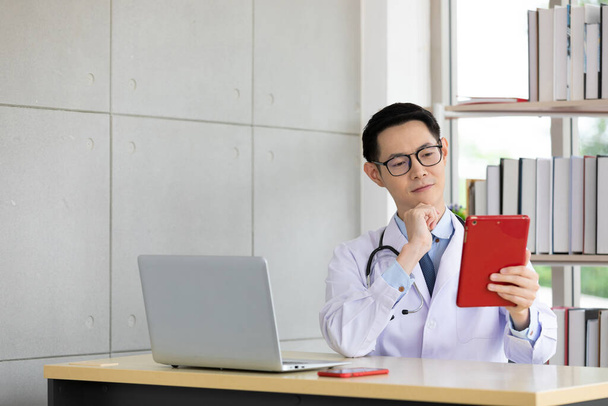 aasialainen lääkäri puhuu potilaan tai hänen perheensä kautta online video chat tabletin sairaalassa - Valokuva, kuva