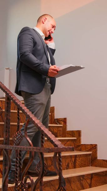 Office executive speaking on smartphone standing on stairs - Fotó, kép