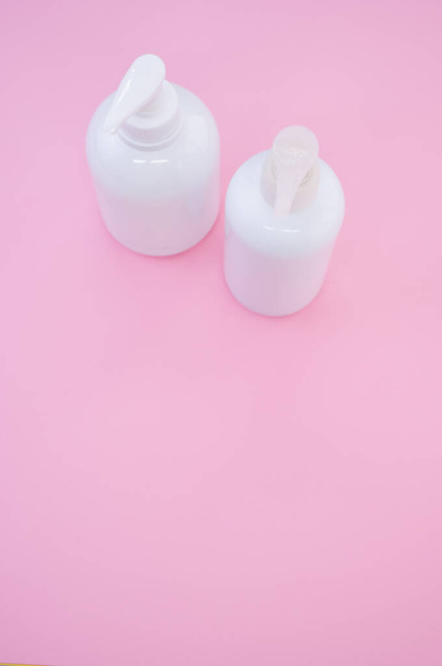 A vertical shot of white plastic bottles on a pink background - Photo, Image