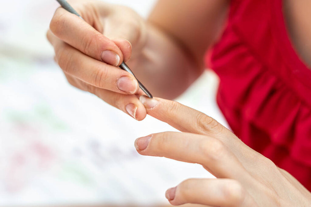 A closeup shot of a female using a cuticle pusher for a nail treatment at home - Fotó, kép