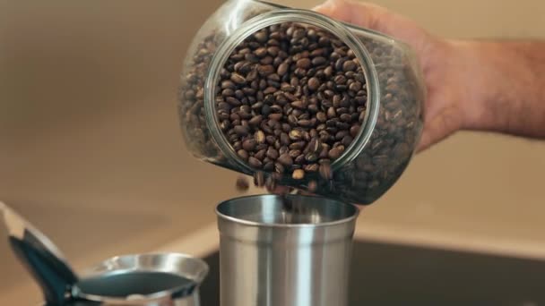 Lähikuva kahvipapuja tölkissä kaadetaan kahvimylly. Kotitekoinen kahvi aamulla. Hidastettu kuvamateriaali - Materiaali, video