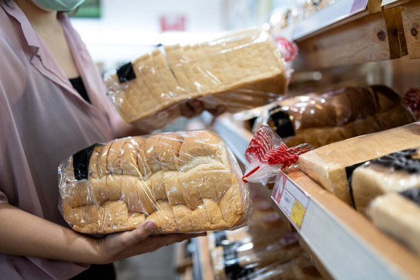 Χέρια του κοριτσιού που κατέχουν φέτες λευκό ψωμί προϊόν, επιλέγοντας ψωμί σιταριού σε πλαστική σακούλα συσκευασμένα, φρέσκο σπιτικό ψωμί στο αρτοποιείο, ενώ τα τρόφιμα ψώνια, γυναίκα που αγοράζουν ή επιλέγοντας την ποιότητα των τροφίμων - Φωτογραφία, εικόνα