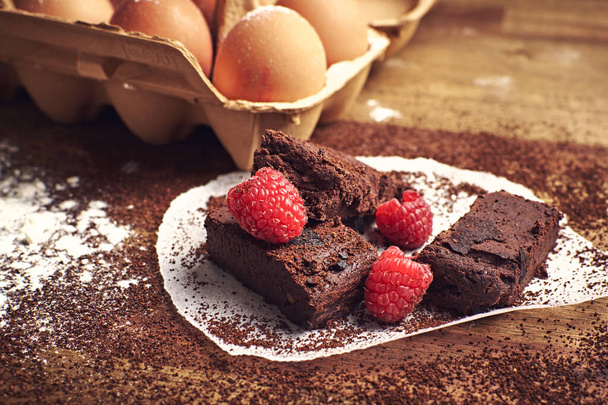 A selective focus shot of eggs and homemade chocolate brownie dessert with raspberries - Фото, зображення