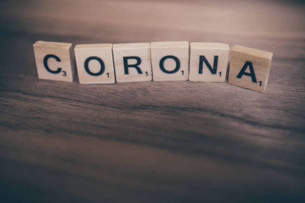 A scrabble letters on wooden background spelling word CORONA - Foto, Imagem