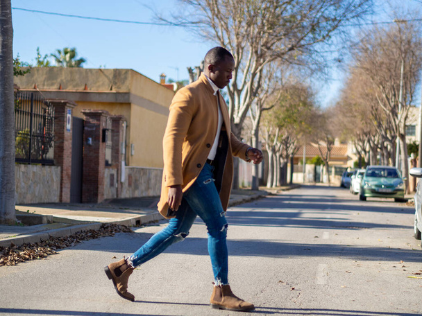 A shallow focus of a stylish adult African male crossing the street under the sunlight - Фото, зображення