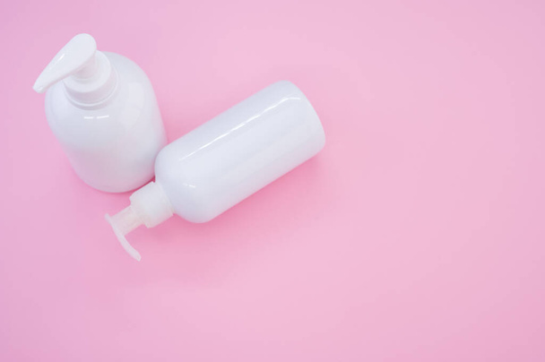 Висококутний знімок білих пластикових пляшок на рожевому фоні
 - Фото, зображення