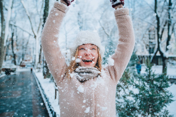 young happy girl laughs and throws snow on herself. snow in the foreground - Фото, изображение