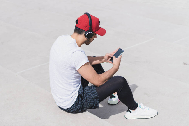 A young attractive male listening to music after a workout outdoors - Φωτογραφία, εικόνα