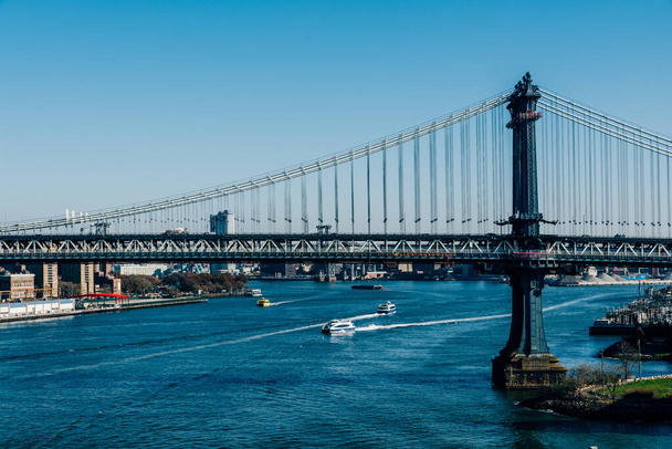 The Brooklyn Bridge, boats in the East River, and buildings of New York, USA - Foto, Bild