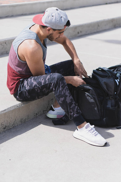 A vertical shot of a young male with a backpack preparing to workout outdoors - Foto, afbeelding