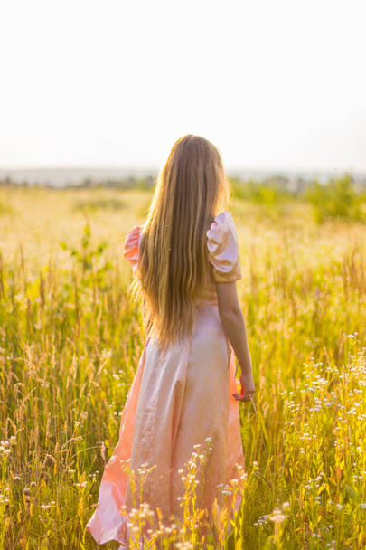 meisje staan in het veld in een roze jurk - Foto, afbeelding
