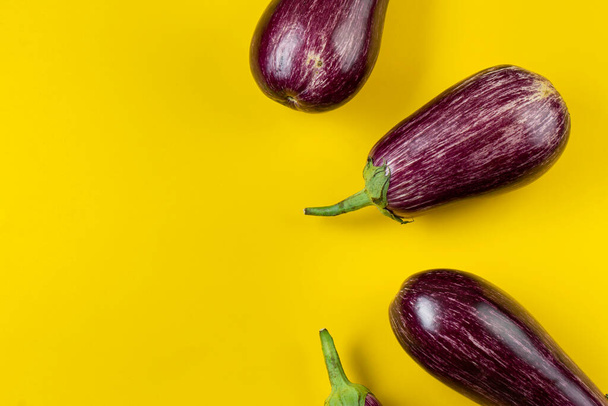 Raw purple eggplant on a yellow background. Fresh vegetables. Space for text. Top view. - Foto, immagini