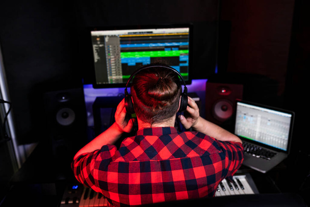 Hipster DJ z długimi włosami słucha swojej nowej piosenki na stereo, którą właśnie nagrał w studio. - Zdjęcie, obraz