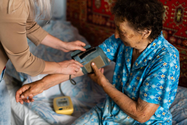 Female doctor measuring blood pressure of senior woman - Fotó, kép