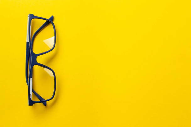 Fashionable glasses in blue frames for vision on a yellow background. Health concept. The medical field that studies the eyes. - Фото, зображення