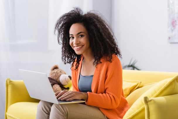 fröhliche junge afrikanisch-amerikanische Freelancer mit Laptop zu Hause - Foto, Bild