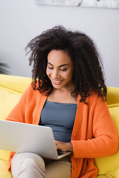 positive african american freelancer using laptop at home - Foto, afbeelding