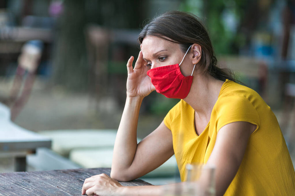 young woman wearing a face mask feeling sad during coronavirus epidemic - Фото, зображення
