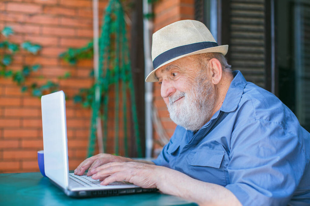senior man enjoying using notebook outdoors - Foto, afbeelding