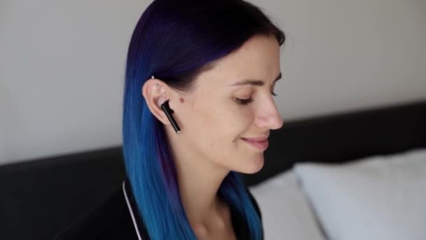 Młoda kobieta z niebieskimi włosami zdejmuje słuchawki bezprzewodowe - Materiał filmowy, wideo