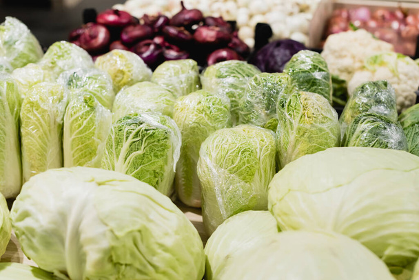 野菜の近くの新鮮なキャベツのビューを閉じるスーパーマーケットでぼやけた背景に  - 写真・画像