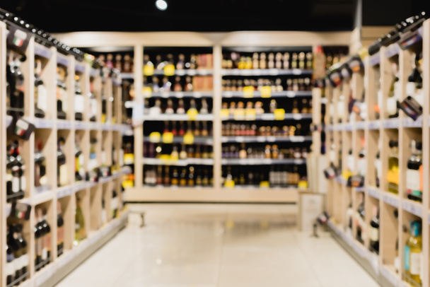 Blurred background of bottles on shelves in supermarket  - Фото, зображення