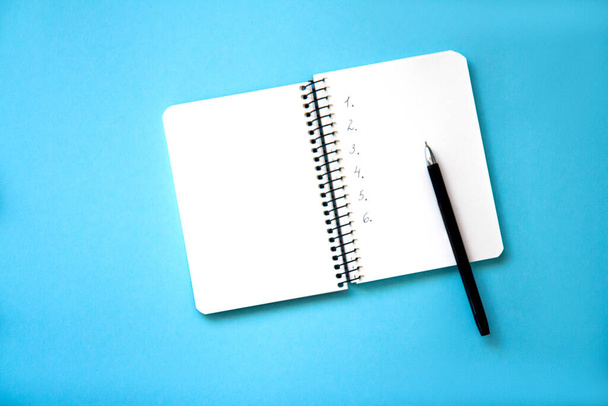 Open spiral notebook with blank white pages and pen on blue background. Flat lay - Photo, Image