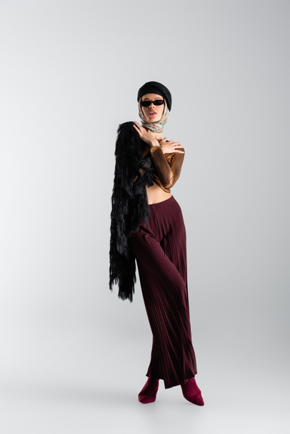 full length of elegant woman in sunglasses and beret posing on grey - Photo, Image